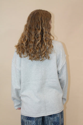 Person wearing a light blue jacket and jeans with a beige background