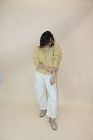 Person wearing a yellow sweater and white pants on a beige floor.