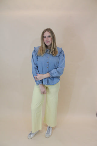 Person wearing a blue jacket and yellow pants on a beige background