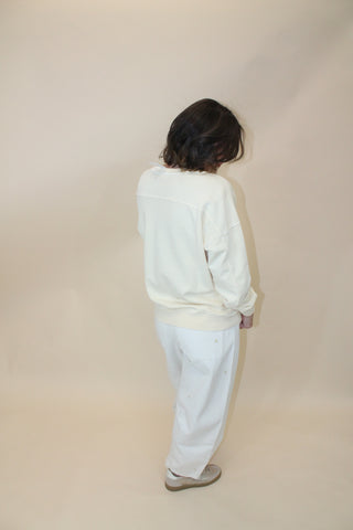 Person wearing a white outfit against a beige wall