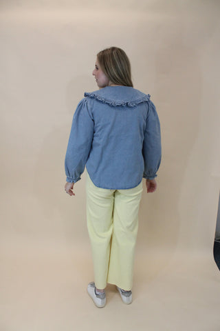 Person wearing a blue jacket and yellow pants on a beige background