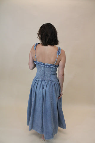 Woman wearing a blue dress with thin straps on a beige background