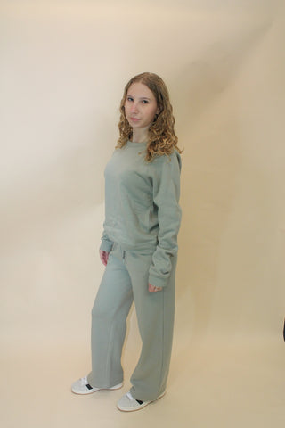 Person wearing a light blue tracksuit standing against a plain background