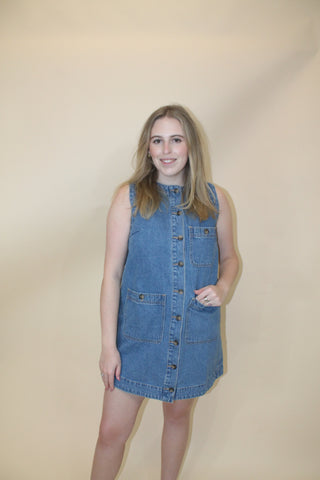 Person wearing a blue denim dress against a plain background