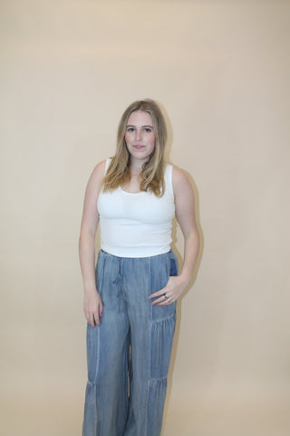 Woman wearing a white top and blue jeans on a beige background