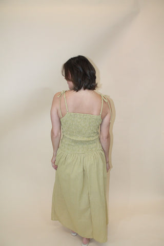 Woman wearing a light green dress lying on a beige floor.
