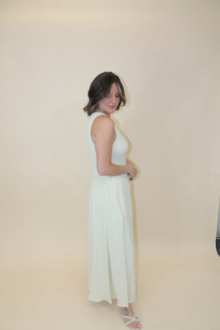 Woman in a white dress standing on a beige floor.