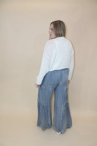 Woman holding a pair of blue jeans on a beige background