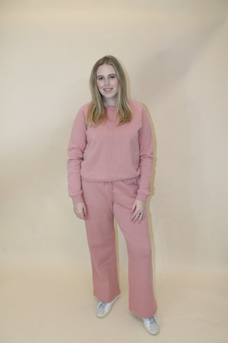 Person wearing a pink outfit on a beige background