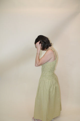 Person wearing a light green dress against a plain background