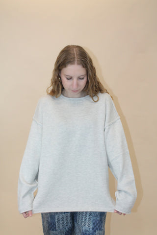 Woman wearing a light gray sweater against a beige background