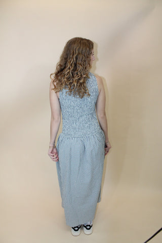 Person wearing a light blue sleeveless top and plaid pants on a beige floor.